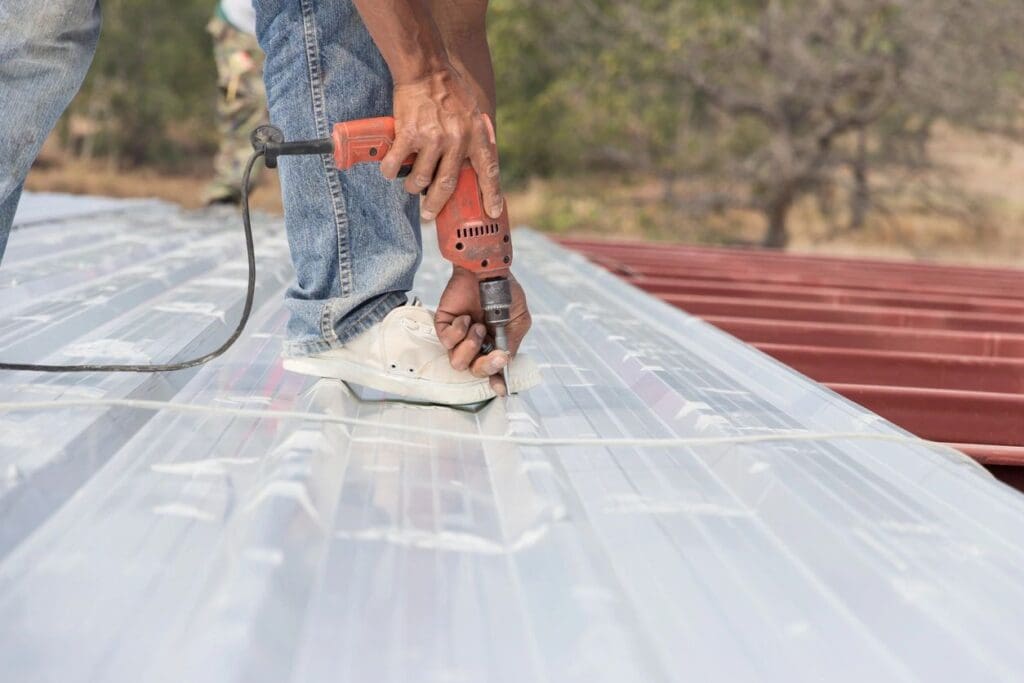 A man is using an electric drill to fix the roof of his house.